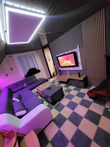 sala de estar con sofá púrpura y TV en Alpinejka House, en Tržič