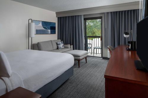 a hotel room with a bed and a chair and a desk at Courtyard by Marriott Covington / Mandeville in Covington