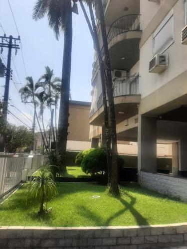 un edificio con palmeras frente a un patio en Apto Amplo, confortável, bem localizado, Astúrias en Guarujá