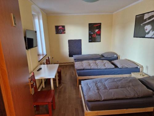 a room with three beds and a table and a tv at Penzion Kornout in Bílina