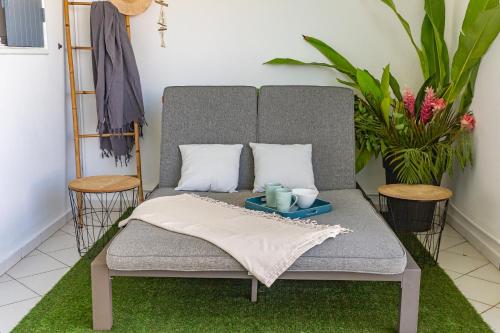 a gray couch with two pillows and two candles on it at Zandoli Exotic Résidence in Sainte-Anne