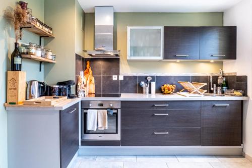 a kitchen with dark wood cabinets and appliances at Bohemian Cocon Annecy - spacieux T2 - balcon avec vue dégagée - place de parking in Meythet