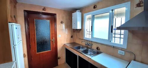 Elle comprend une petite cuisine avec un évier et une fenêtre. dans l'établissement Casa típica Andaluza El Lucero, à Rute