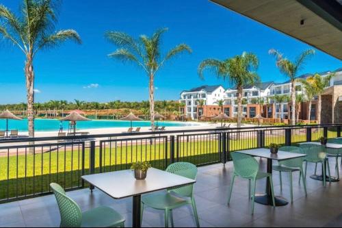 a balcony with tables and chairs and a swimming pool at Serenity @The Blyde Crystal Lagoon in Pretoria