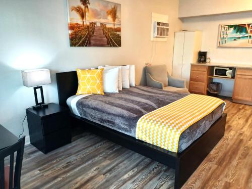 a hotel room with a bed with a yellow and gray blanket at Johns Pass Beach Motel in St. Pete Beach