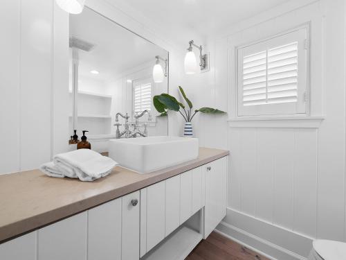 a white bathroom with a sink and a mirror at Kennebeck Oasis - Private Patio, Steps 2 Sand & AC in San Diego