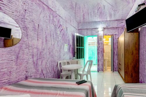 a purple room with two beds and a table at Pousada John John in Guarujá