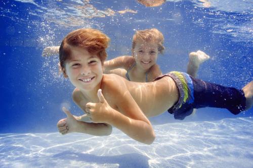 two young boys are swimming in the water at The Sanderling in Duck