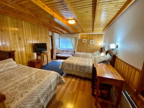 a hotel room with two beds and a television at Hostal Collins House in Temuco