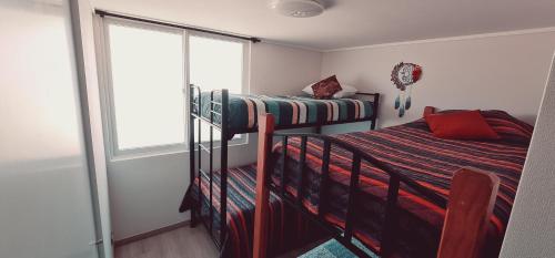 a bedroom with two bunk beds and a window at ACOGEDOR Dpto FRENTE AL MAR EN EL TABO in El Tabo