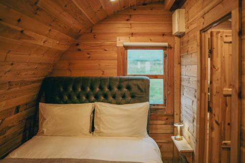 uma cama num chalé de madeira com uma janela em Ceide Glamping em Ballycastle