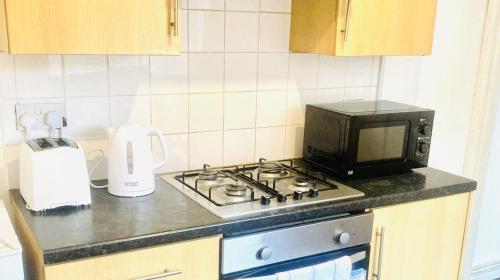 La cocina está equipada con fogones y microondas. en Spacious 2 Bedroom Apt Newcastle Upon Tyne, en Elswick
