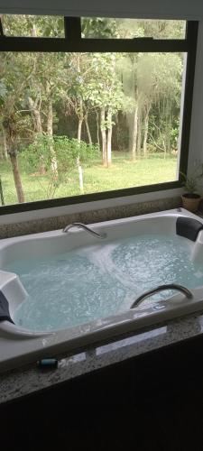 a bath tub filled with water in front of a window at Pousada da Lua São Pedro in São Pedro