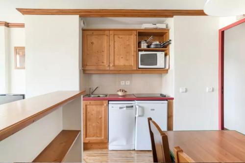 une cuisine avec un réfrigérateur blanc et une table dans l'établissement Résidence Le Rami Les Coches - La Plagne, à La Plagne Tarentaise