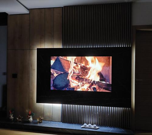 a fireplace with a tv above it with a fire at Zlatibor luxury residence, near the center in Zlatibor