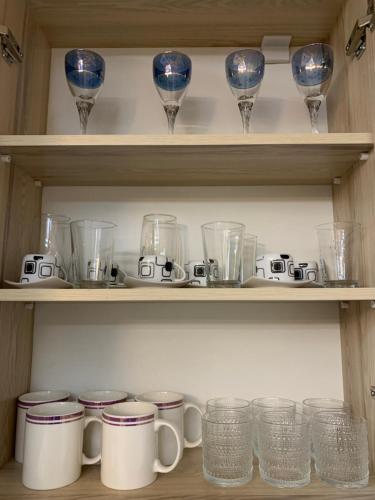 a shelf filled with glasses and other glass items at Ridi's Comfort Apartment in Shkodër