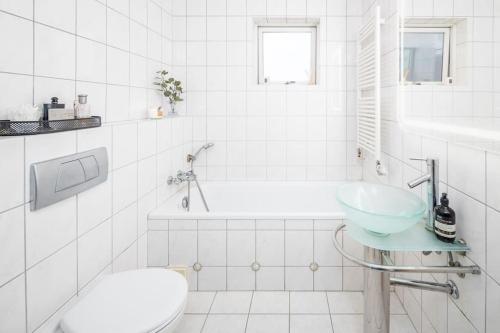 a white bathroom with a sink and a toilet at Kopavogur Cozy Nest (3-bedrooms) in Reykjavík