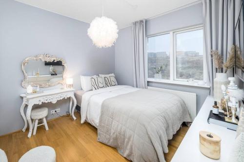 a white bedroom with a bed and a table and a mirror at Kopavogur Cozy Nest (3-bedrooms) in Reykjavík