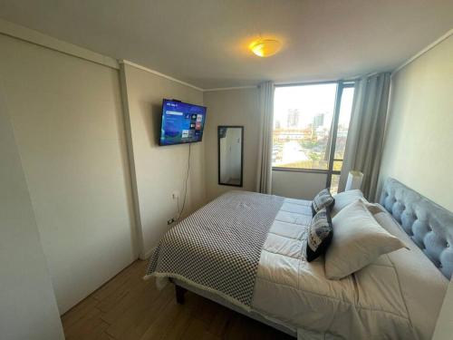 聖地亞哥的住宿－Departamento 2 espacios, 1 pieza，卧室配有一张床,墙上配有电视。