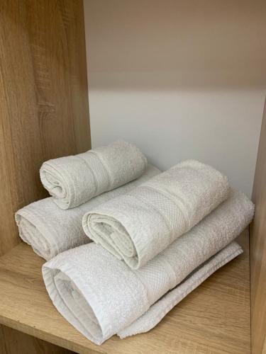 una pila de toallas blancas sentadas en un estante en Ridi's Comfort Apartment, en Shkodër