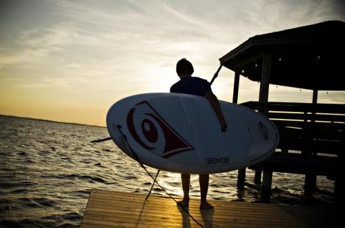 a man standing on a dock holding a surfboard at The Sanderling in Duck