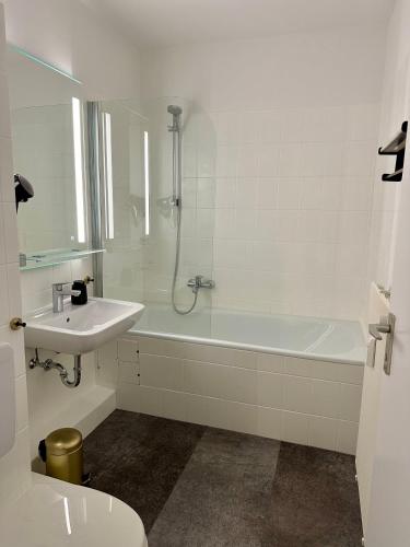 ein weißes Badezimmer mit einer Badewanne und einem Waschbecken in der Unterkunft Ferienwohnung Bad Sachsa Harz II in Bad Sachsa