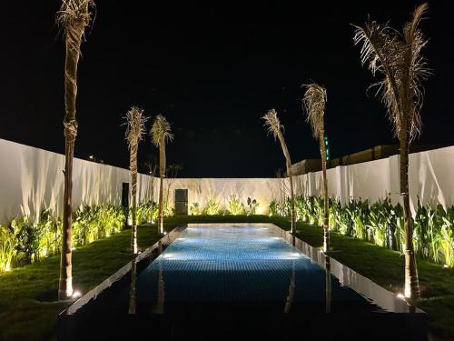 una piscina con palmeras frente a un edificio en شاليه مزدانة, en La Meca