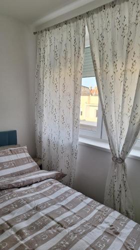 a bedroom with two beds and a window with curtains at Apartman u Zemunu in Zemun