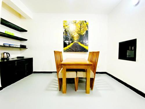 a wooden table and chair in a room with a painting at Drew Apartment Tanga in Tanga