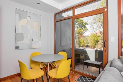 a living room with a table and yellow chairs at Santa Lucia Suites - Barranco in Cuenca
