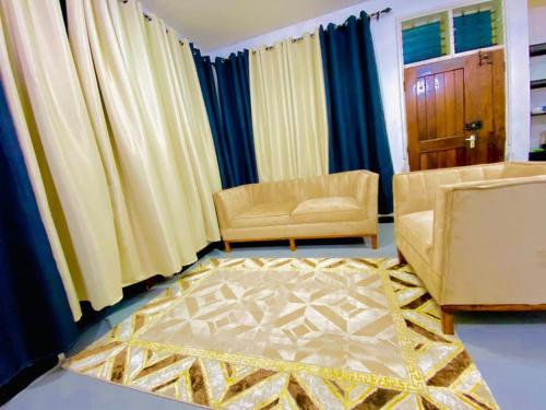 sala de estar con 2 sillas y alfombra en Drew Apartment Tanga, en Tanga