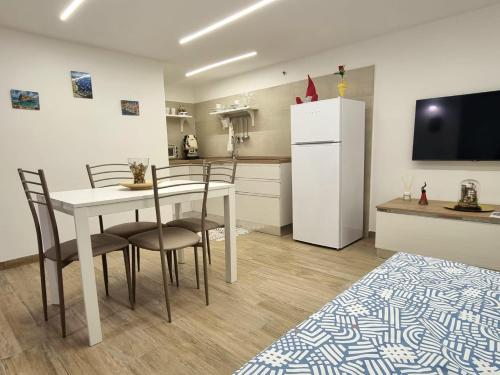 uma cozinha com uma mesa e cadeiras e um frigorífico branco em Casa comoda e centrale in quartiere storico di Napoli em Nápoles