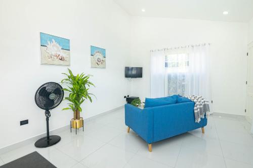 a living room with a blue couch and a fan at Apartamentos Cristal in Quepos