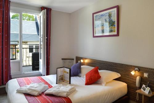 a bedroom with two beds and a window at Logis Hotel Au Site Normand in Clécy