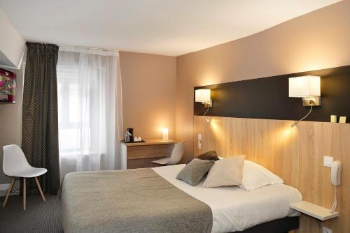 a hotel room with a large bed and a desk at Logis Hotel Spa Restaurant Au Site Normand in Clécy