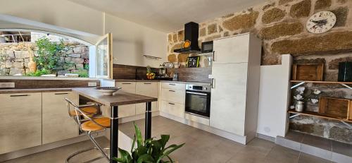 une cuisine avec une table et une horloge au mur dans l'établissement T2 typique au cœur du village et vue sur le Golfe, à Olmeto