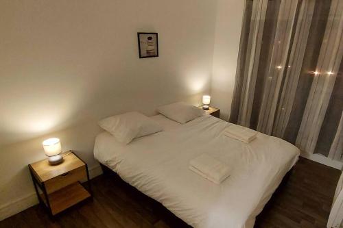um pequeno quarto com uma cama branca e 2 candeeiros em Bel appartement à 9 minutes de Paris em Bois-Colombes