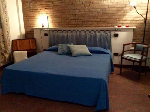 a blue bed in a room with a brick wall at Corte Dossello in Migliaro