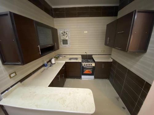 uma pequena cozinha com armários castanhos e um fogão em Furnished Apartment in Cairo, شقة مفروشة بجانب مطار القاهرة no Cairo