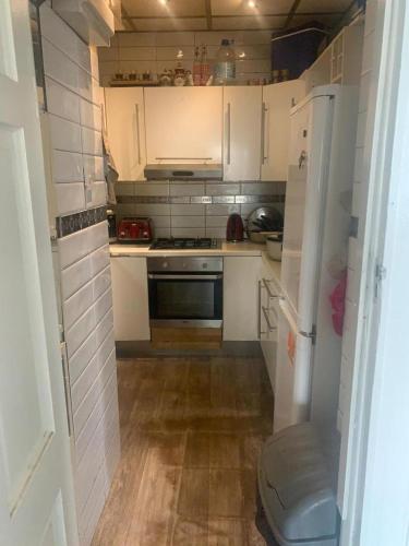 eine kleine Küche mit weißen Schränken und einem Kühlschrank in der Unterkunft Spacious 1 bedroom en-suite, kitchen and garden space in Ilford