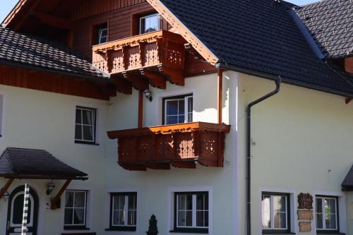 Apartman Tauplitz skiing, hiking, bike, cross country - Haus Sandlweber في Obersdorf: مبنى ابيض عليه بلكونات حمراء