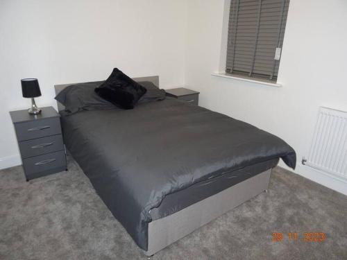 a bed with a black pillow on top of it at Beautiful 4 bed house in Leeds in Cross Gates