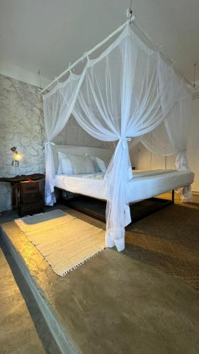 a bedroom with a white bed with a canopy at Mar-Me-Quer, Eco Beach Retreat in Inhambane
