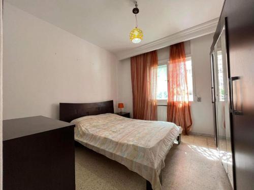 um quarto com uma cama, uma secretária e uma janela em JARDIN Apartments em El Aouina
