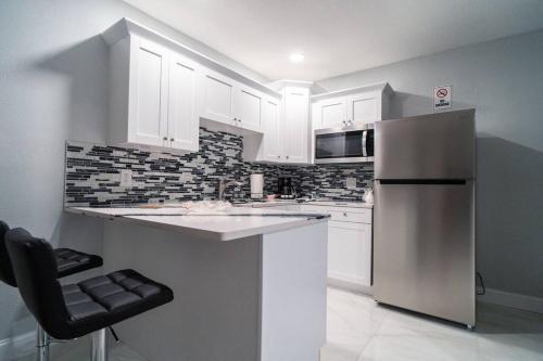 a kitchen with white cabinets and a stainless steel refrigerator at Grey Novo Studio + free-parking&wifi in Tampa
