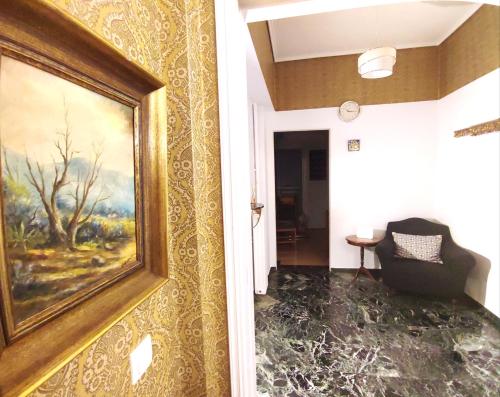een kamer met een schilderij aan de muur en een stoel bij Charm & Comfort near Petralona station in Athene
