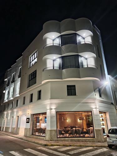 - un grand bâtiment blanc avec des chaises devant dans l'établissement Hotel Suites Moma Centro, à Villanueva de la Serena