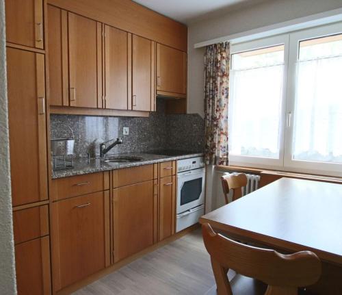 a kitchen with wooden cabinets and a sink and a table at Appartement Mittaghorn Saas-Fee in Saas-Fee