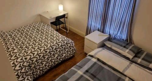 1 dormitorio con 2 camas, escritorio y ventana en 1 Cozy Bedroom near Airport and city Centre 3people en Dublín