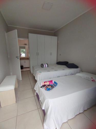 Cette chambre comprend 3 lits avec des armoires blanches. dans l'établissement Cobertura 302 vista mar Canasvieiras, à Florianópolis
